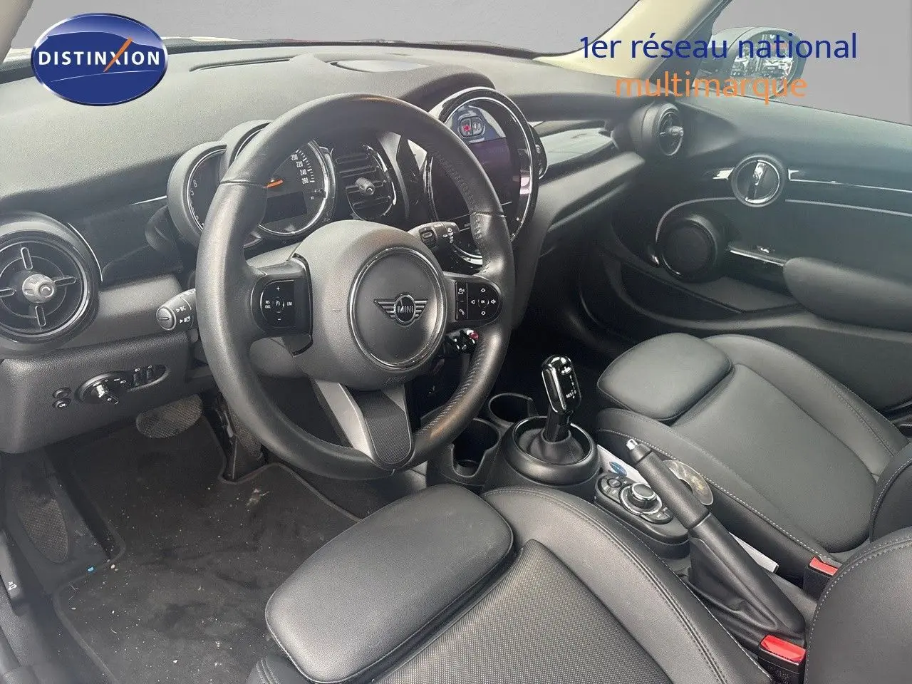 Intérieur noir de la MINI 1.5 136CH 2023 vu côté conducteur, avec volant cuir et console centrale moderne.