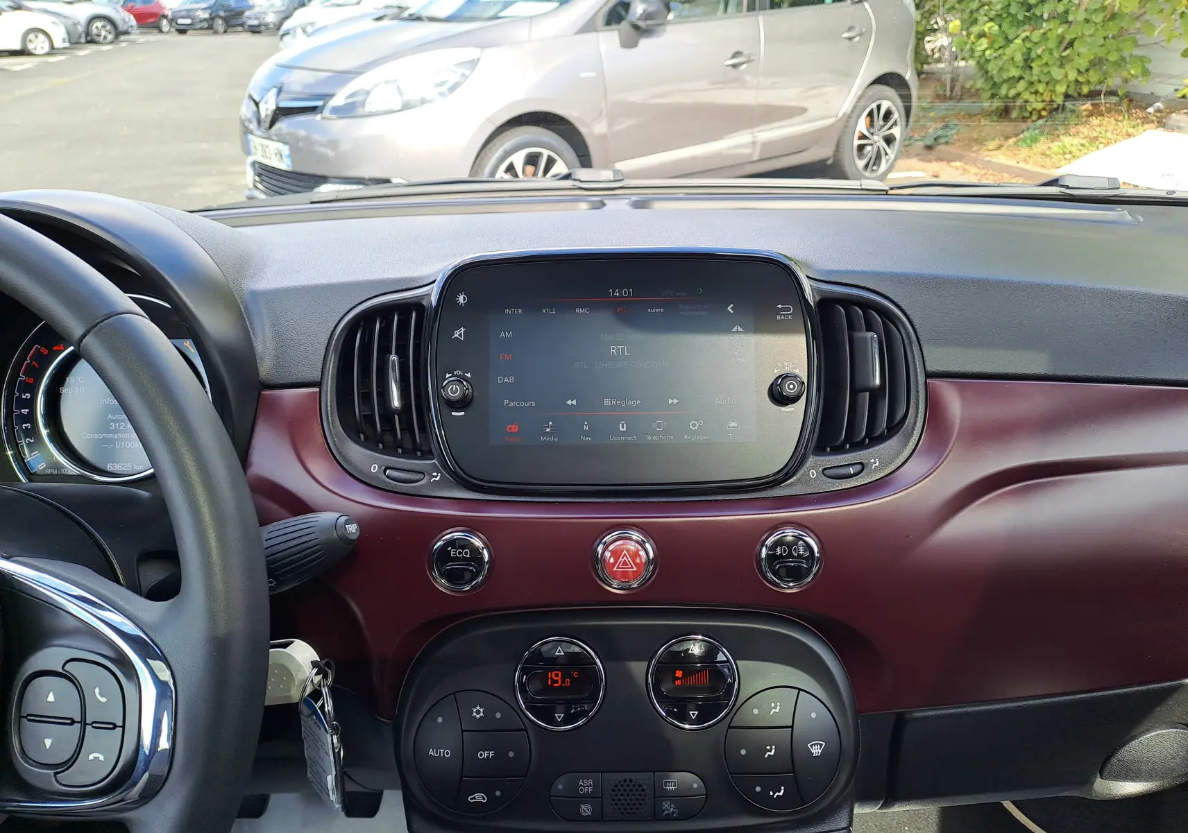 Tableau de bord bordeaux métallisé d'une Fiat 500 2020, vue avant centrée sur l'écran tactile et commandes climatiques.