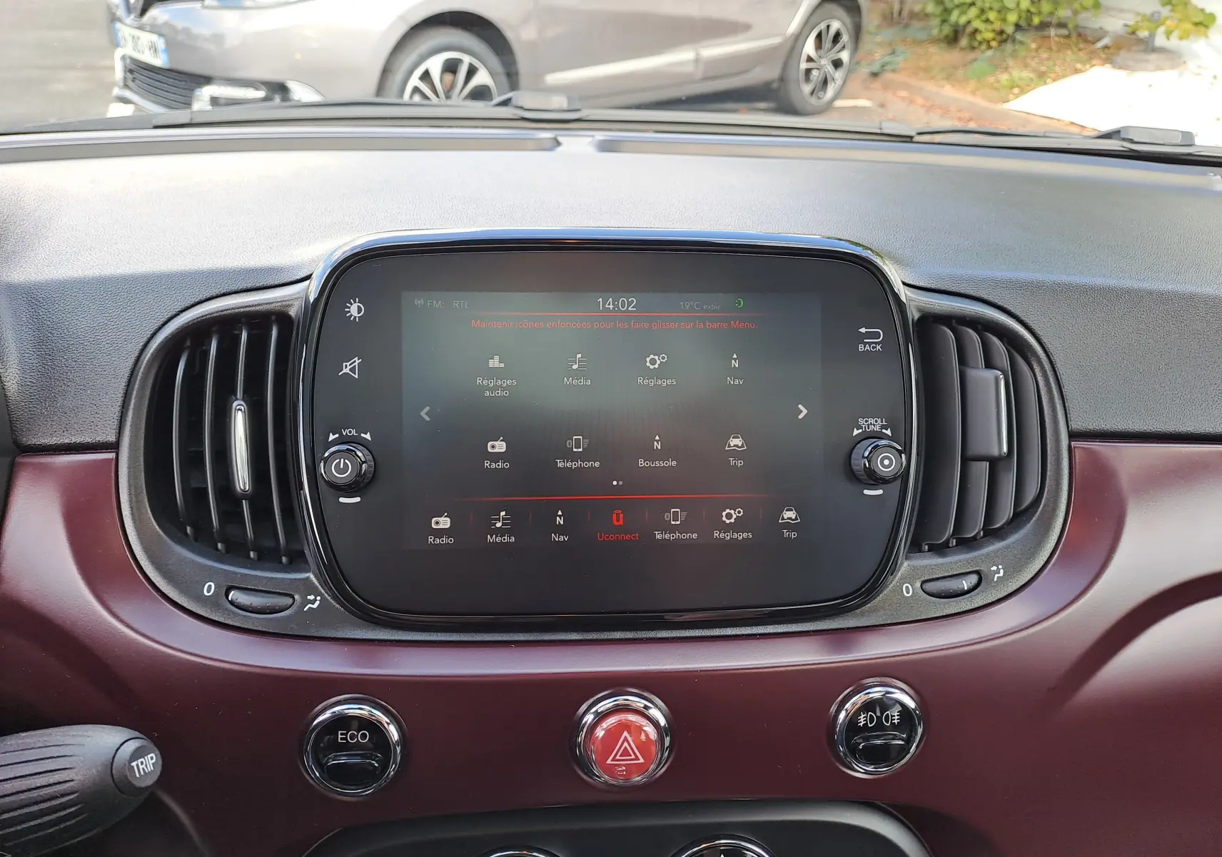 Tableau de bord bordeaux métal de Fiat 500 2020 avec écran tactile central et commandes circulaires visibles.