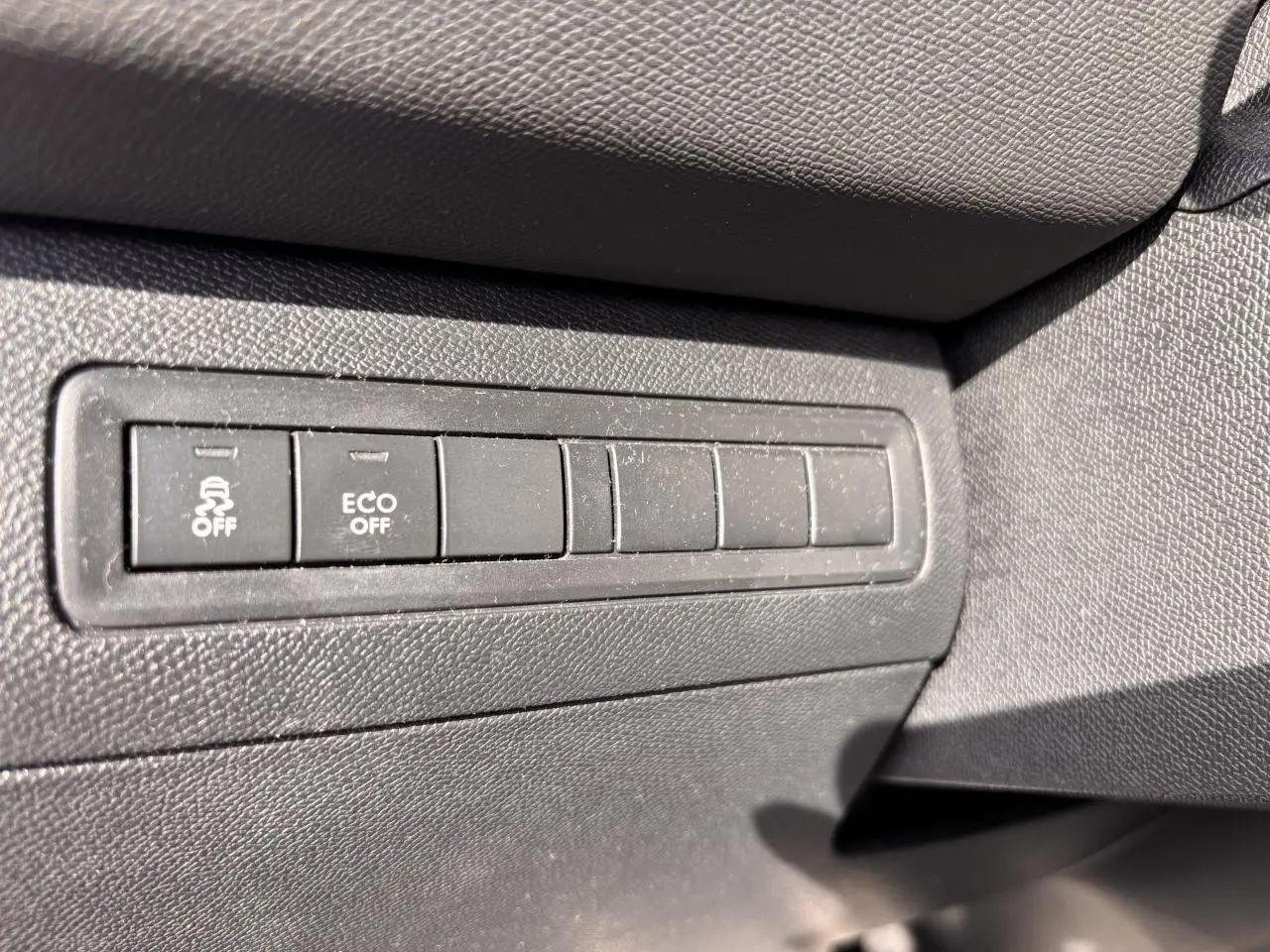 Boutons de commande de désactivation de l'ESP et mode ECO sur la planche de bord d'une Peugeot 308 rouge foncé GT Line.