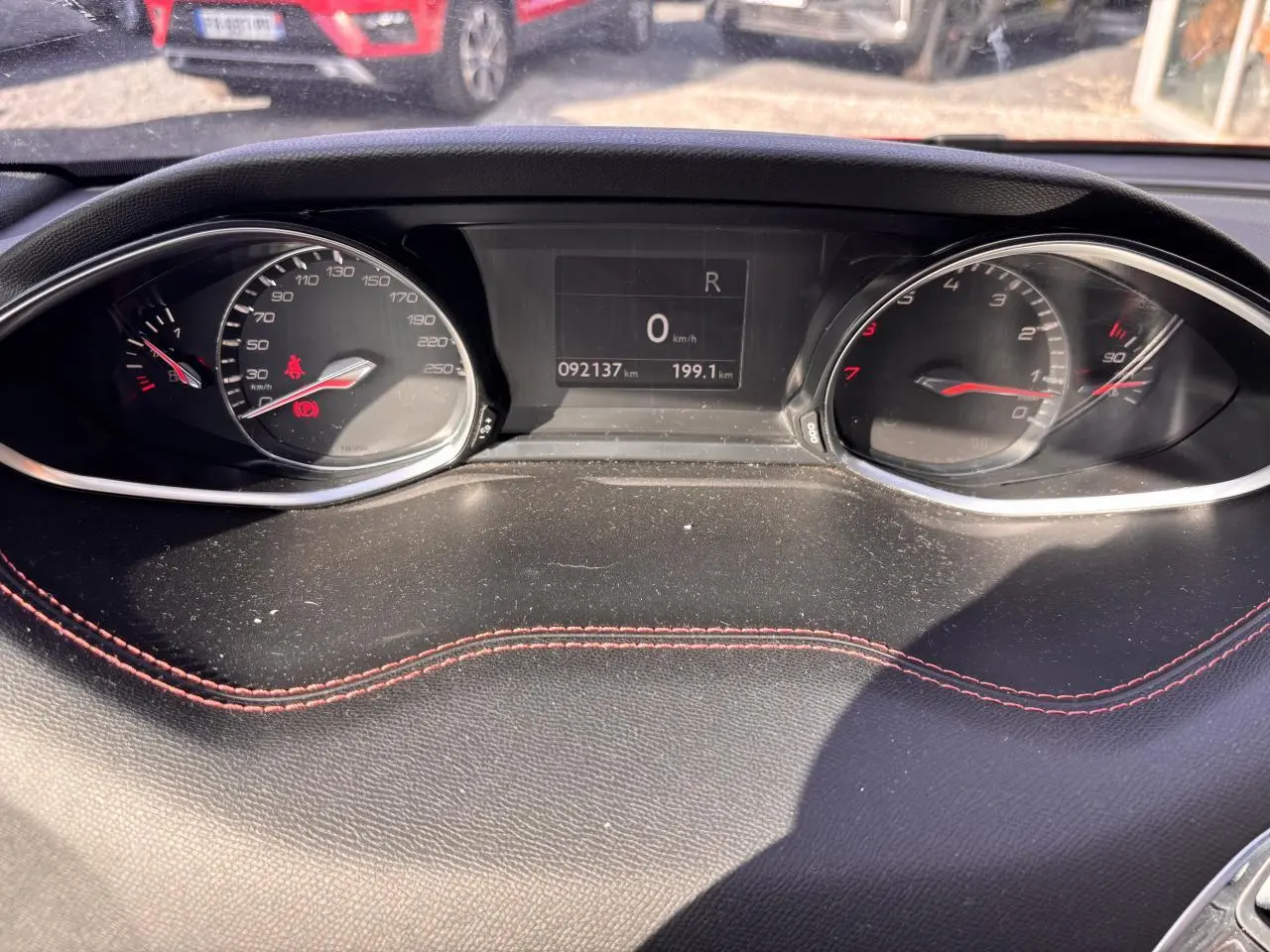 Tableau de bord de Peugeot 308 GT Line 2016 avec compteur digital et surpiqûres rouges sur cuir noir.
