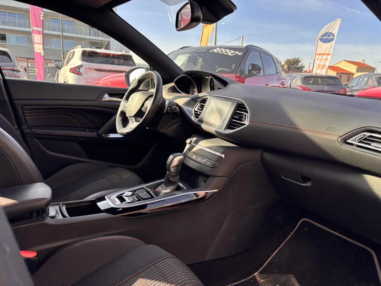 Intérieur avant droit de Peugeot 308 GT Line 2016 avec tableau de bord noir et surpiqûres rouges visibles.