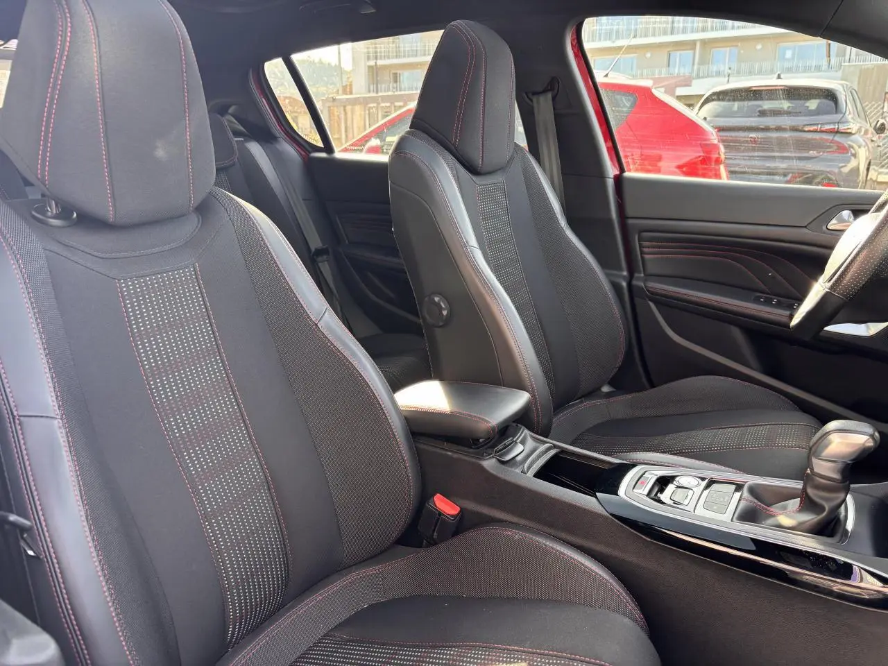 Intérieur de la Peugeot 308 GT Line 2016, vue côté droit sur sièges sport noirs avec surpiqûres rouges et console centrale.