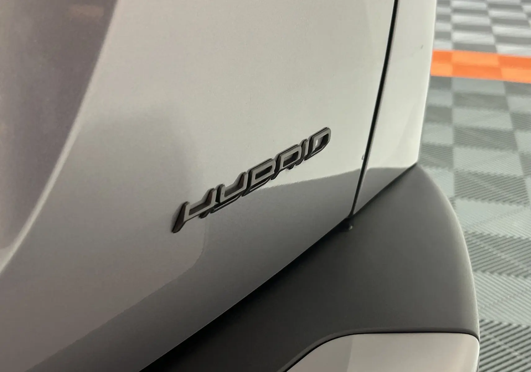Gros plan sur l’inscription "HYBRID" en noir sur la carrosserie grise arrière d’un Peugeot 2008 2025.