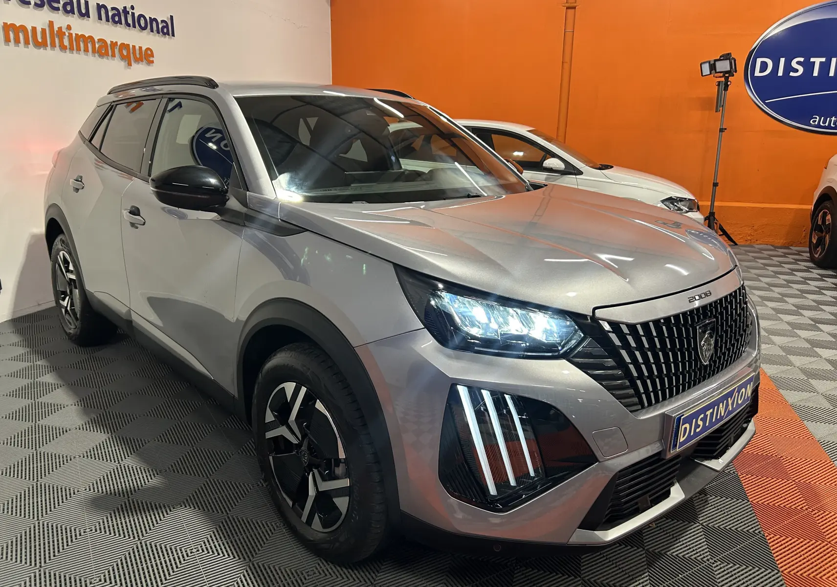 Peugeot 2008 Allure Hybrid gris vue 3/4 avant droit avec phares LED allumés et calandre distinctive.