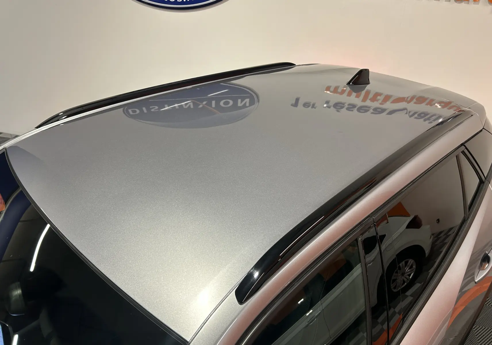 Toit gris métallisé du Peugeot 2008 Allure Hybrid 145 vu en plongée, avec barres de toit noires et vitres teintées.