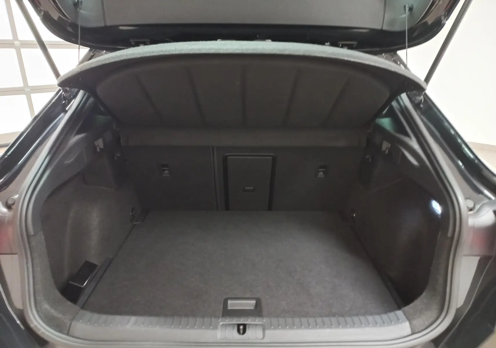 Coffre ouvert vu de l'arrière d'un CUPRA Formentor noir Minuit, montrant un espace de chargement spacieux et éclairé.