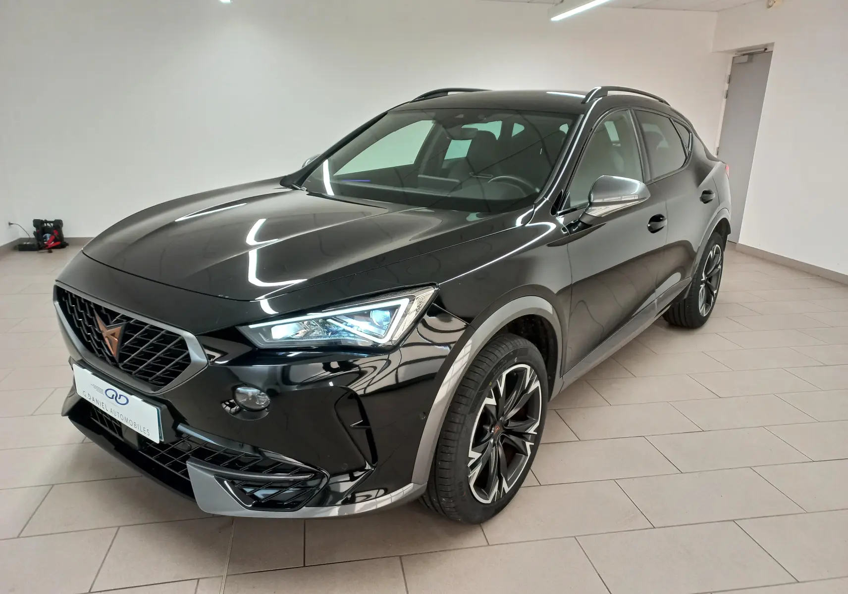 Vue 3/4 avant droit d'un CUPRA Formentor noir minuit avec jantes 18'' Performance Black dans un showroom.