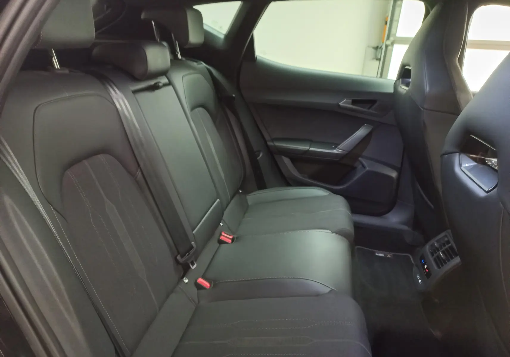 Vue intérieure côté droit des sièges arrière noirs du CUPRA Formentor 2023 avec éclairage d'ambiance et finitions soignées.