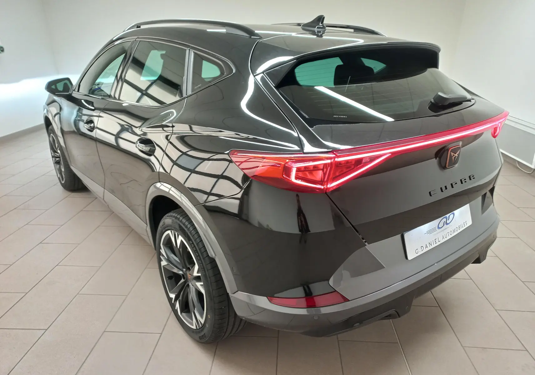 Vue 3/4 arrière droite du CUPRA Formentor noir minuit avec jantes alliage 18'' Performance Black et feux arrière LED continus.