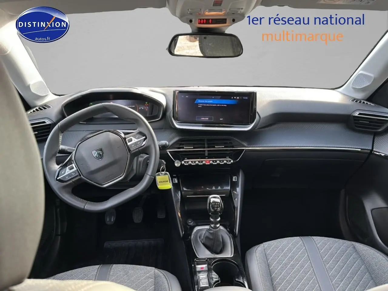 Vue intérieure avant de la Peugeot 208 2024 noire, avec tableau de bord moderne et boîte manuelle visible.