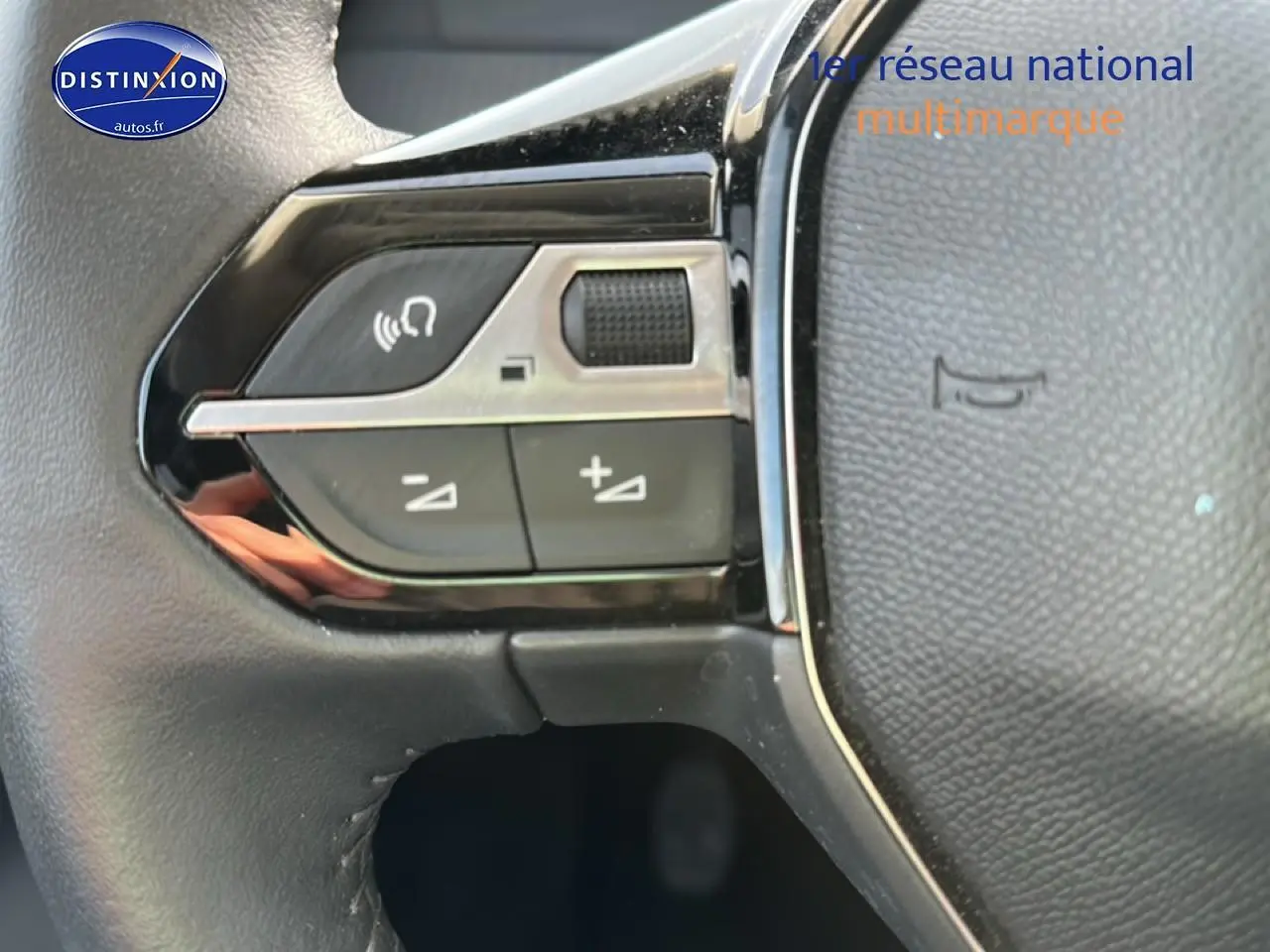 Gros plan sur les commandes multifonctions gauche du volant noir de la Peugeot 208 1.2 PureTech 100 Allure 2024.