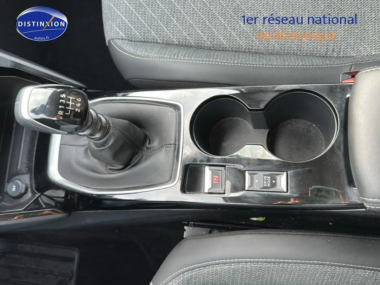 Gros plan sur la console centrale noire de la Peugeot 208 1.2 PureTech 100 Allure avec levier de vitesse manuel et porte-gobelets.