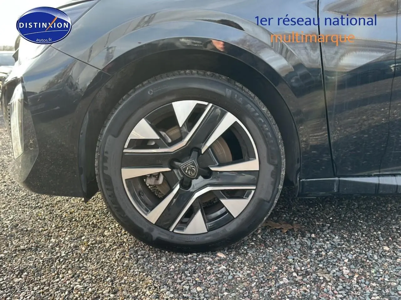 Gros plan sur la roue avant gauche avec jante alu bicolore du Peugeot 208 noir 1.2 PureTech 100 Allure 2024.