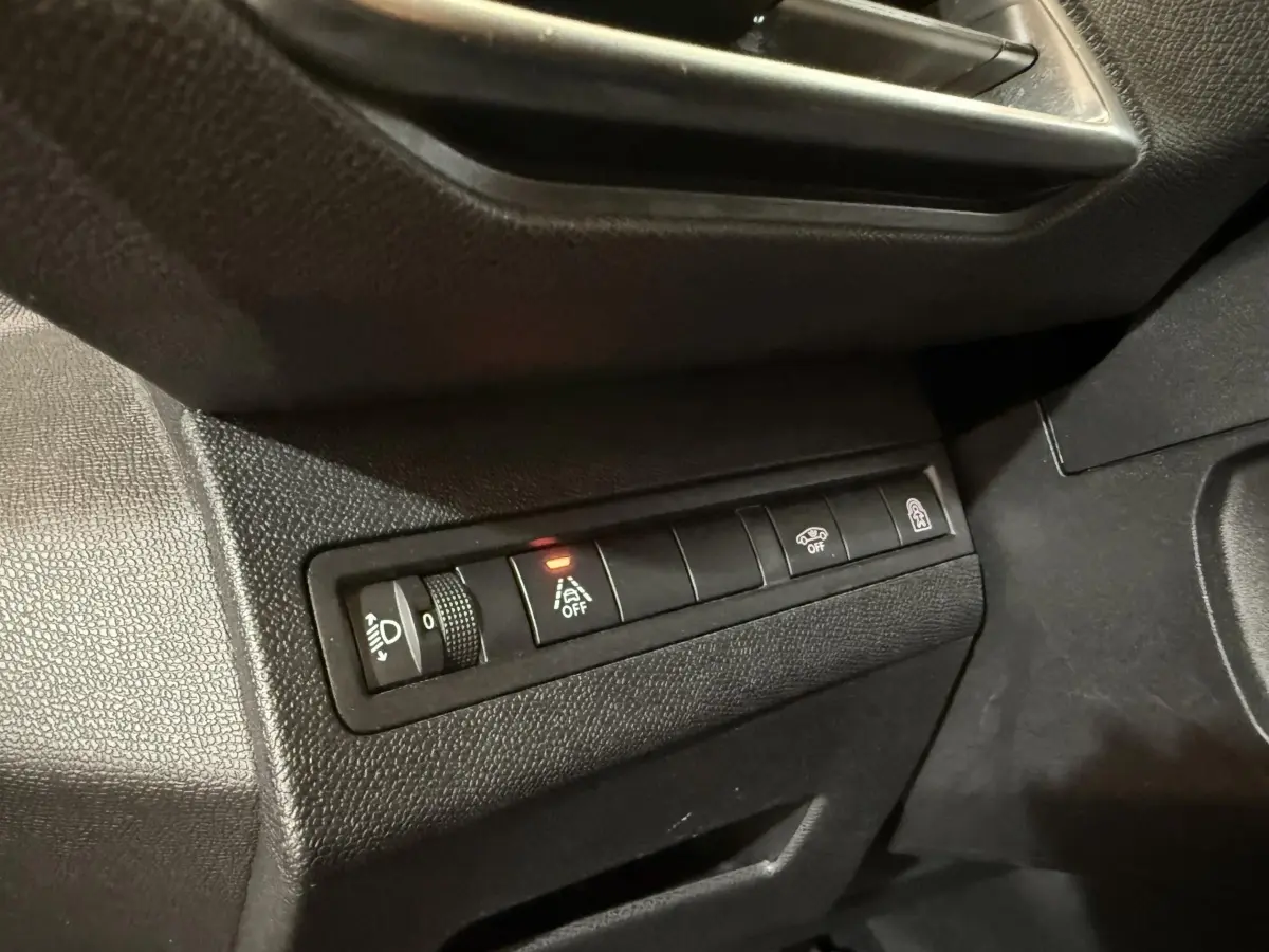 Gros plan sur les commandes noires du tableau de bord côté conducteur du Peugeot 5008 gris clair, avec bouton d’aide au maintien de voie désactivé.