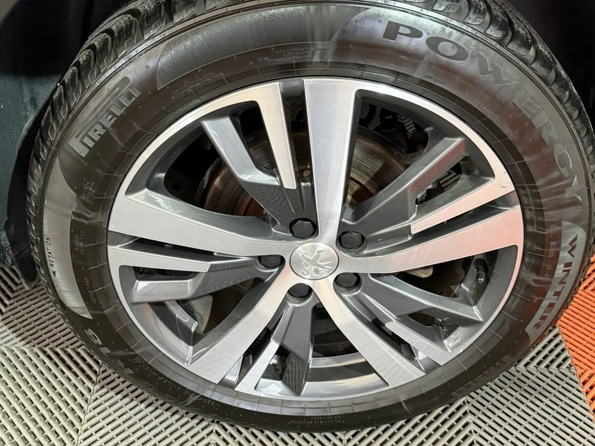 Gros plan sur la jante alliage argentée avec logo Peugeot au centre, montée sur pneu hiver Pirelli Powergy.