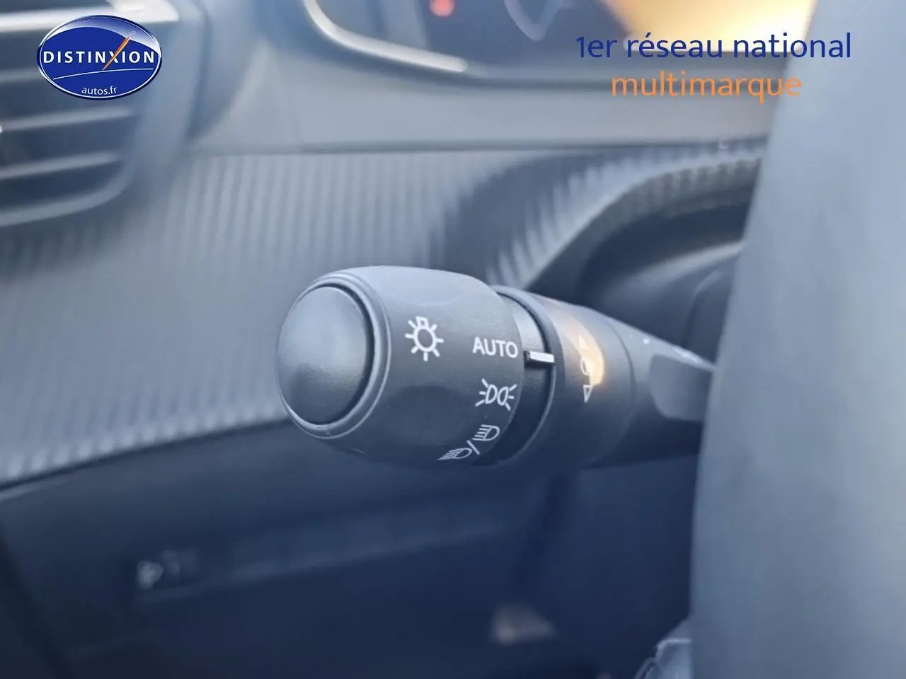 Gros plan sur la commande des phares avec fonction automatique dans l’habitacle gris d’une Peugeot 208 1.2 100 Allure 2025.