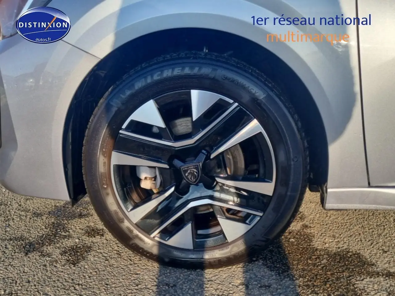 Gros plan sur la roue avant droite gris artense d’une Peugeot 208 1.2 100 allure avec jante alu noire et argent.