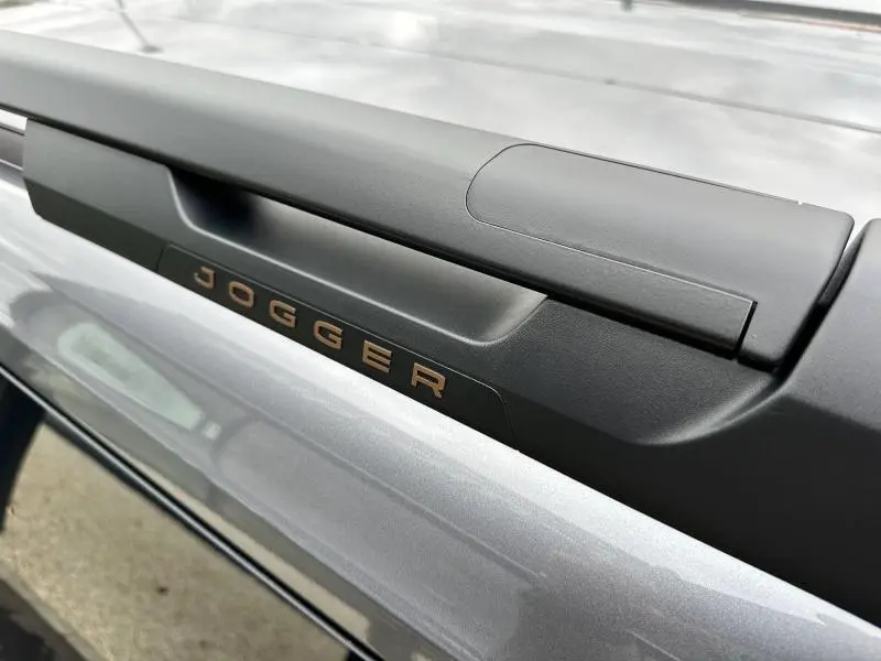 Gros plan sur la poignée arrière gris schiste métallisé du Dacia Jogger avec logo "JOGGER" en relief bronze.