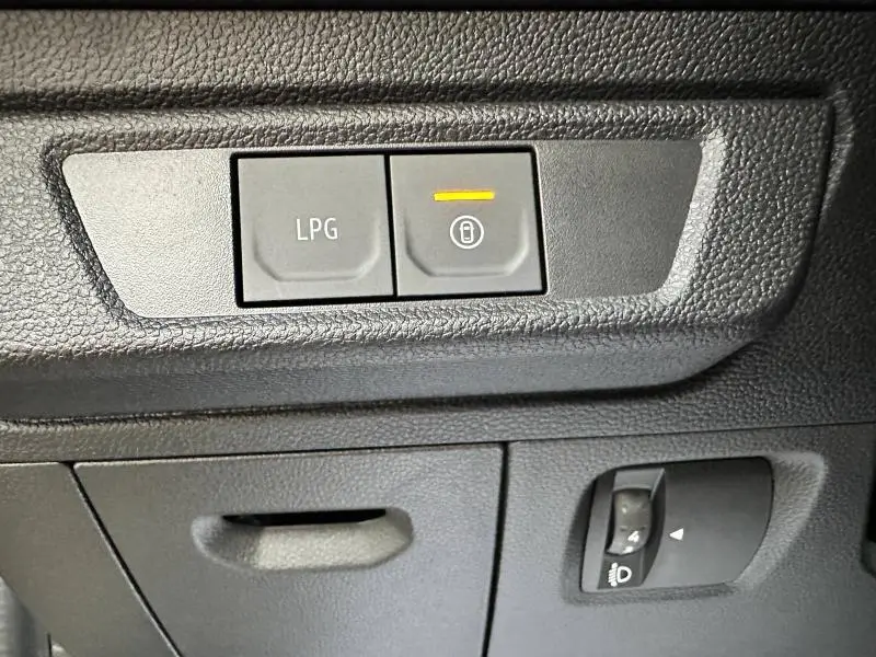 Gros plan sur les boutons de commande LPG et verrouillage, tableau de bord noir du Dacia Jogger gris Schiste métallisé.