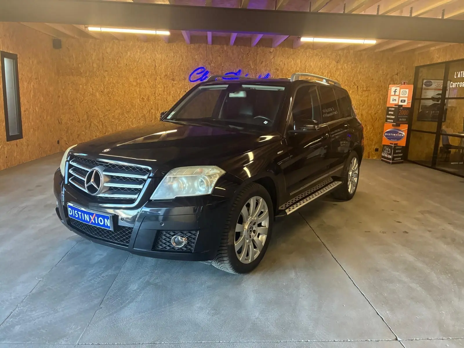 Mercedes GLK noir vue 3/4 avant droit dans un garage avec calandre chromée et jantes alliage.