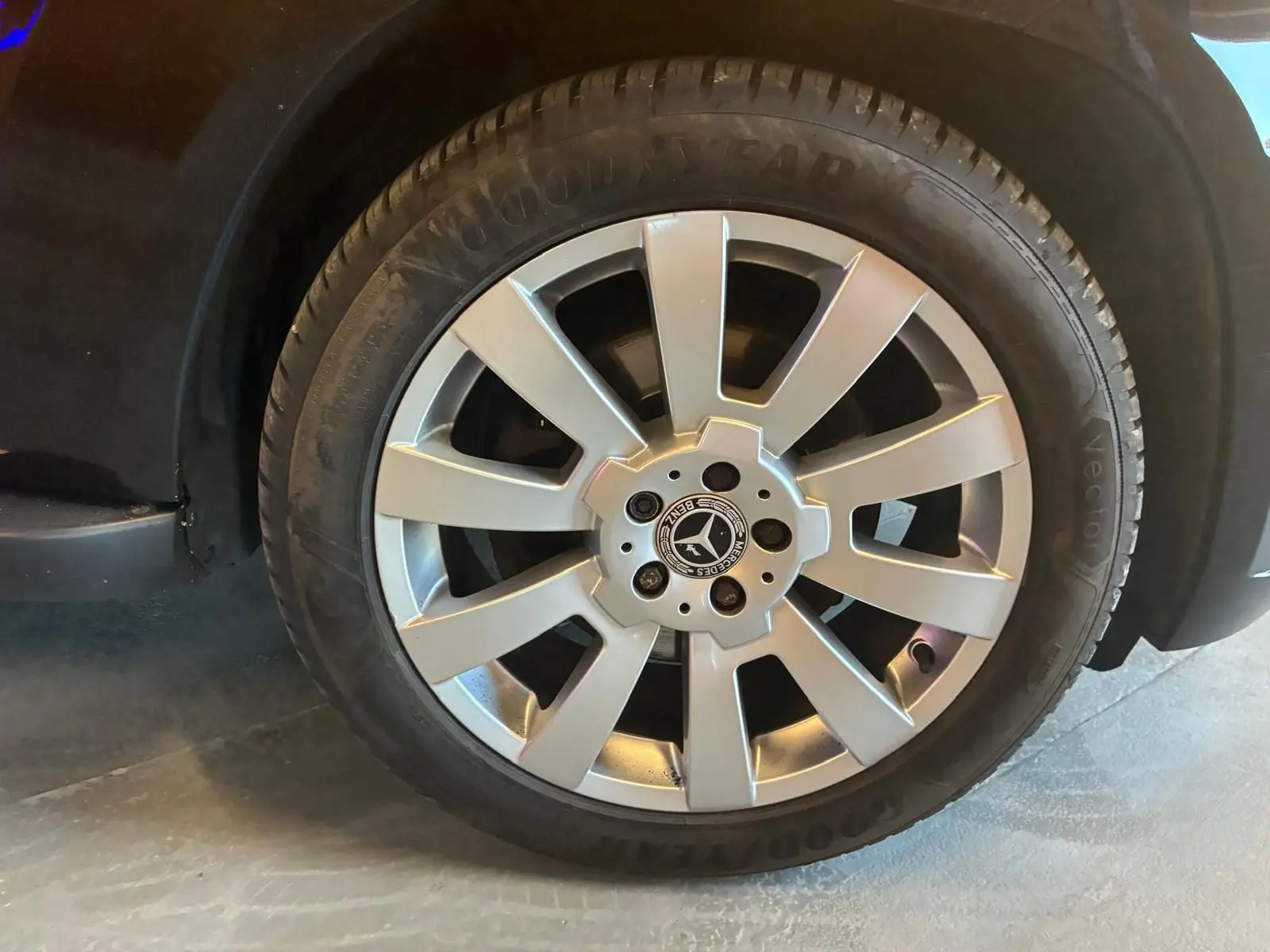 Gros plan sur la roue avant droite d’un Mercedes GLK noir, jante alliage argentée avec logo Mercedes central.