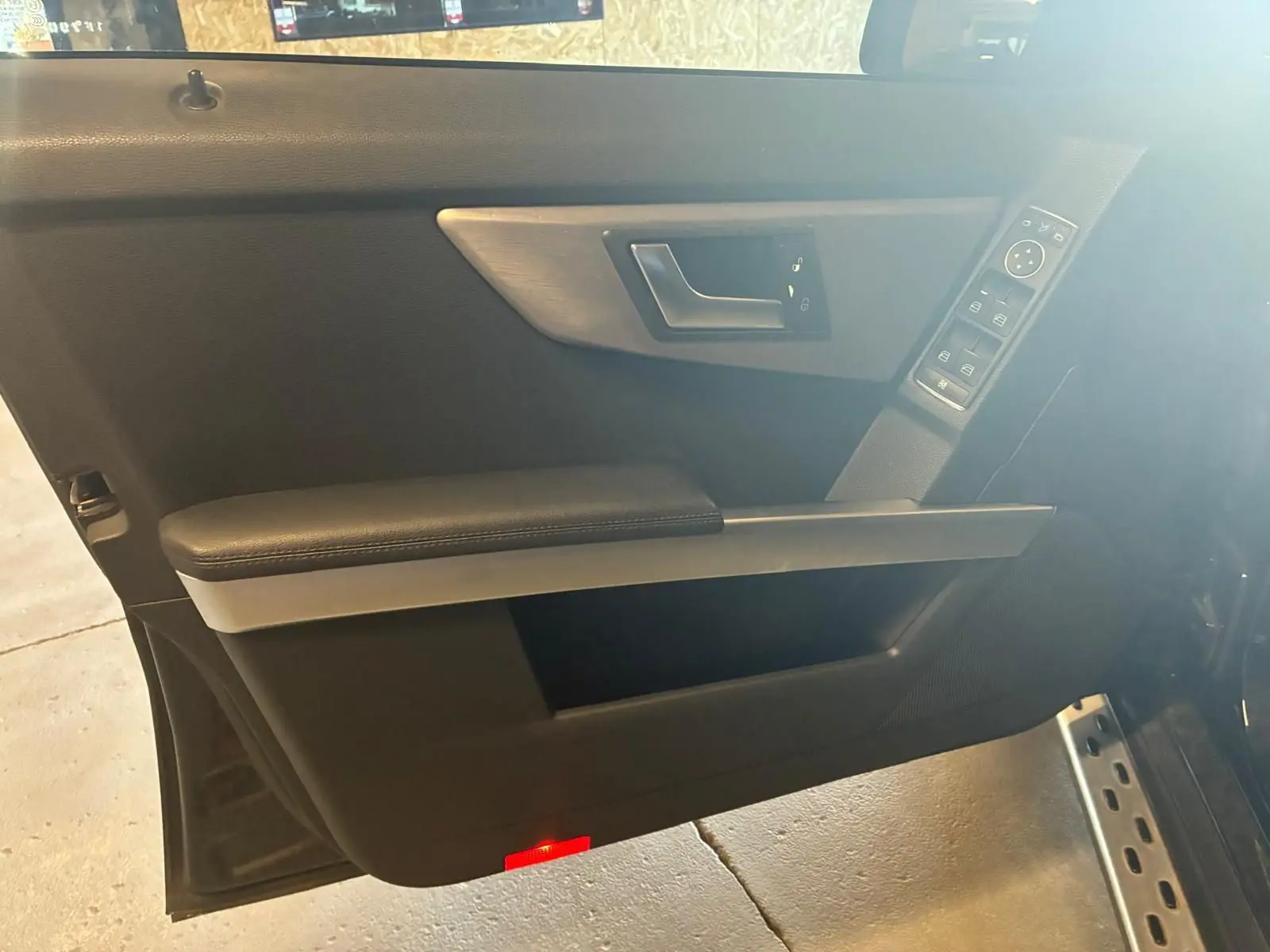 Vue intérieure de la porte avant gauche noire du Mercedes GLK 2012, avec commandes de vitres et poignée argentée.