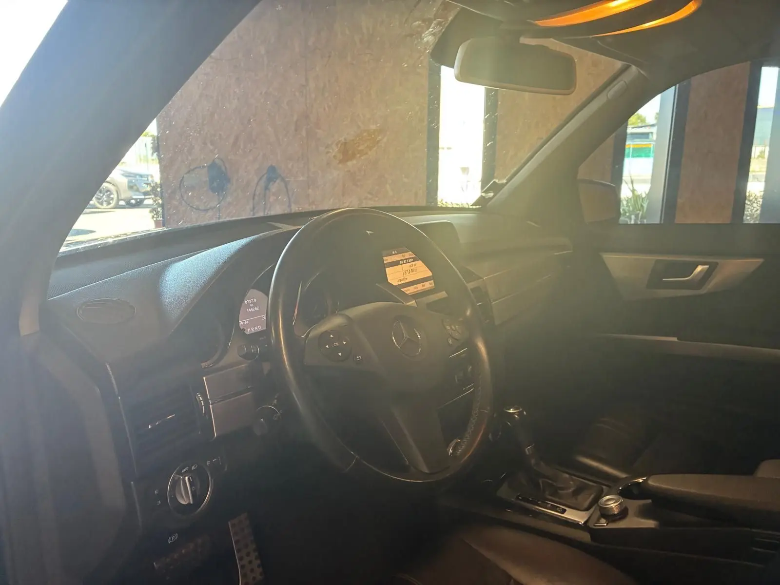 Vue intérieure côté conducteur du Mercedes GLK noir de 2012, mettant en valeur le volant cuir et la console centrale.