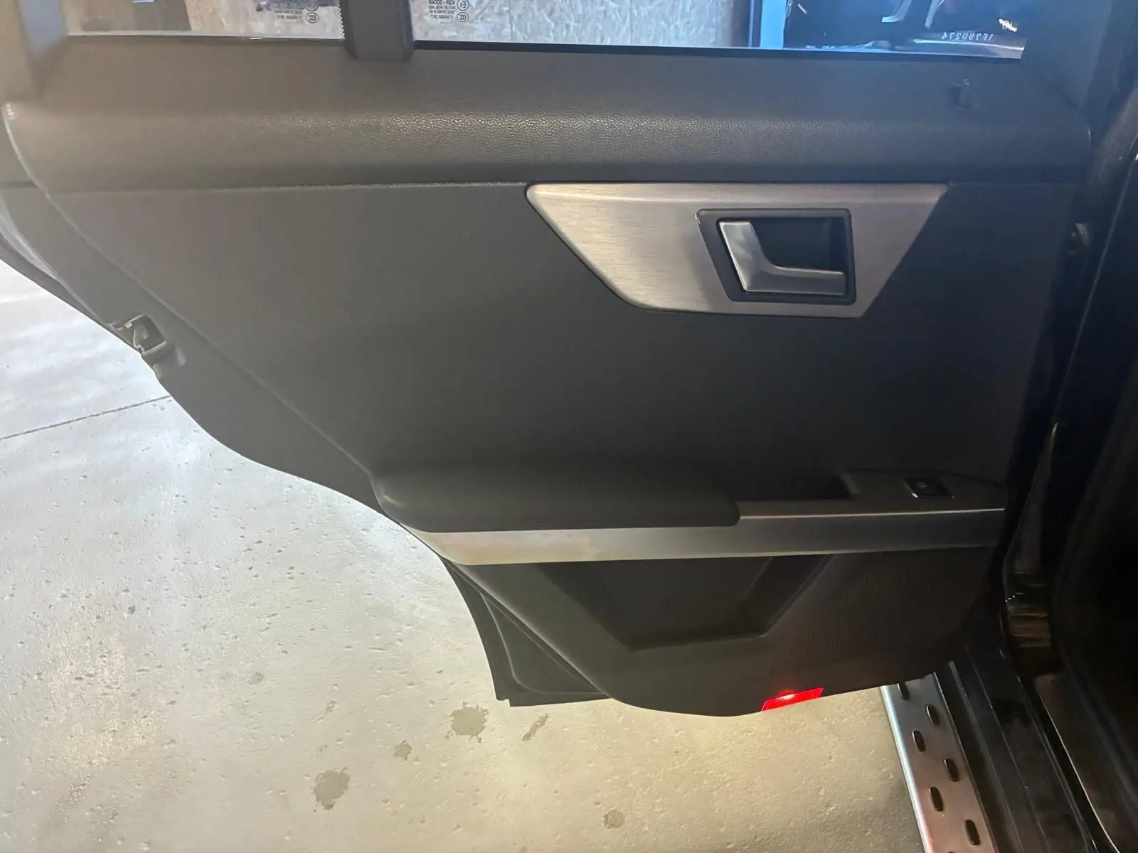 Vue intérieure de la porte arrière droite noire du Mercedes GLK 220 CDI avec insert aluminium et éclairage rouge.