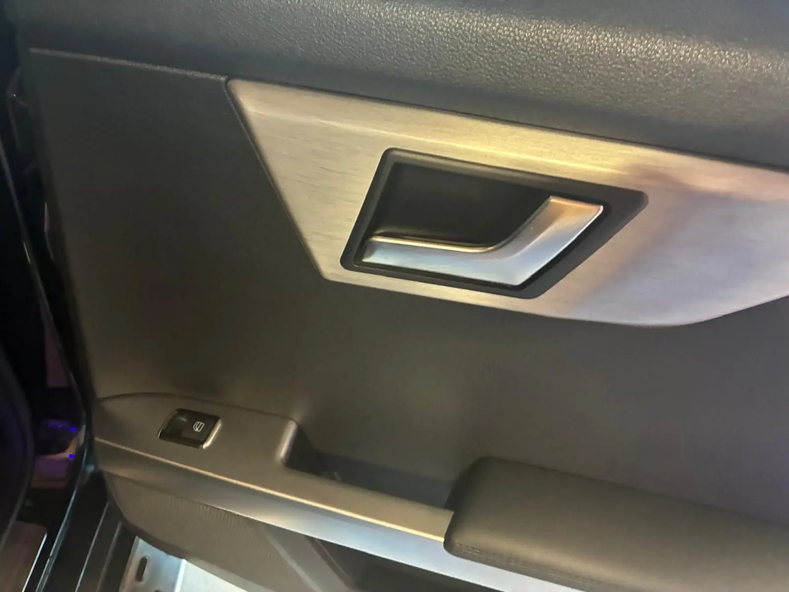 Gros plan sur la poignée intérieure côté gauche d’une Mercedes GLK noire avec bouton de commande de vitre.