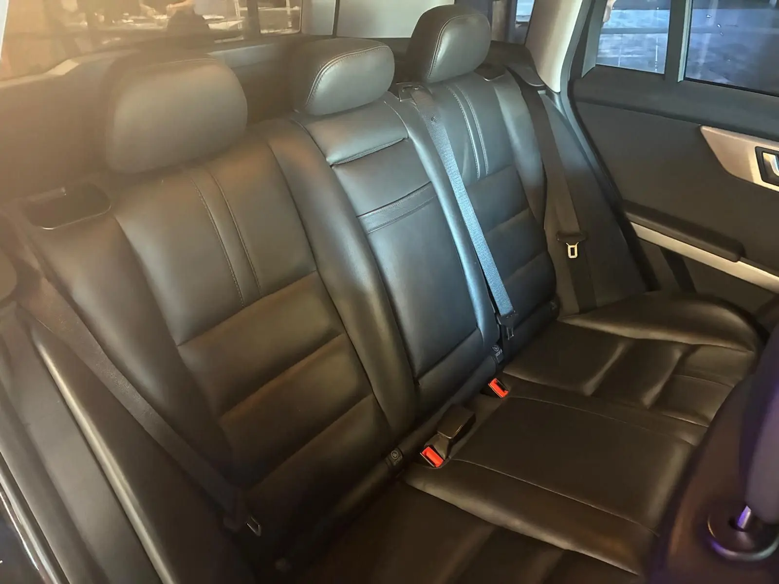 Vue intérieure sur la banquette arrière en cuir noir du Mercedes GLK 220 CDI, avec ceintures et appuie-têtes visibles.