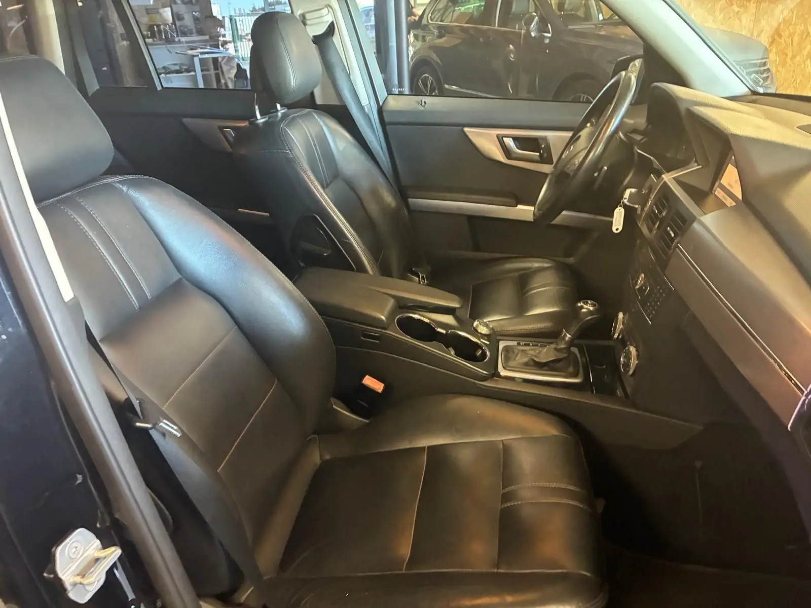 Vue intérieure côté conducteur du Mercedes GLK 220 CDI noir de 2012 avec sièges cuir noir et console centrale visible.