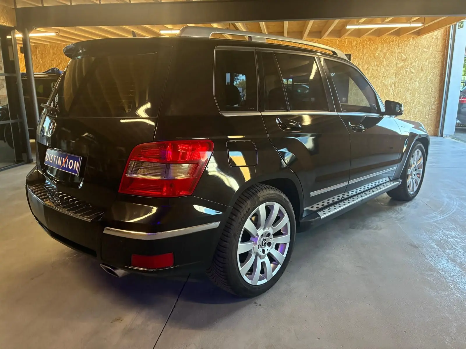 Vue 3/4 arrière droite d’un Mercedes GLK noir 2012 avec jantes alliage et marchepieds métalliques visibles.