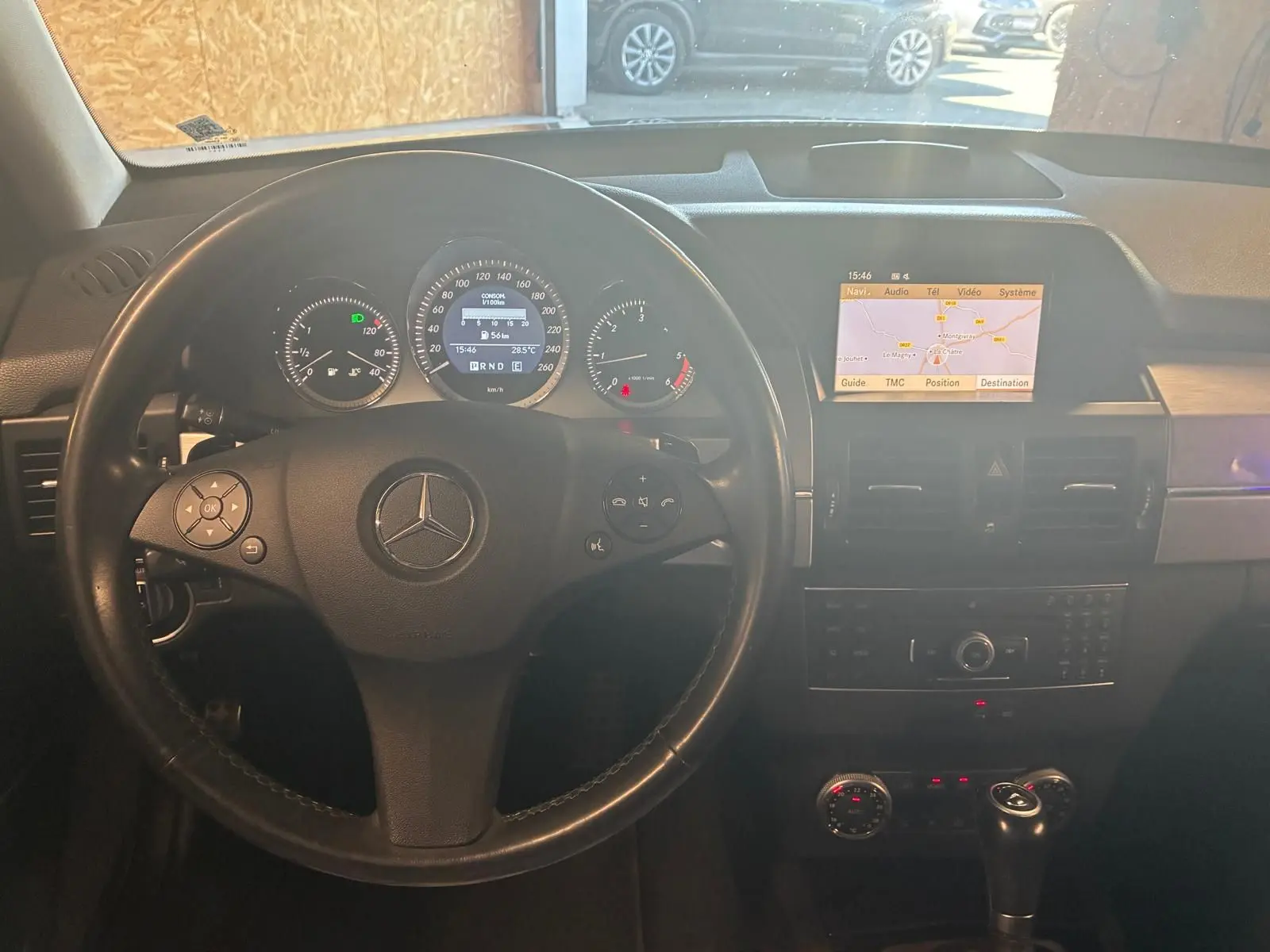 Vue intérieure du tableau de bord noir d'un Mercedes GLK 220 CDI 2012, avec volant cuir et écran GPS allumé.