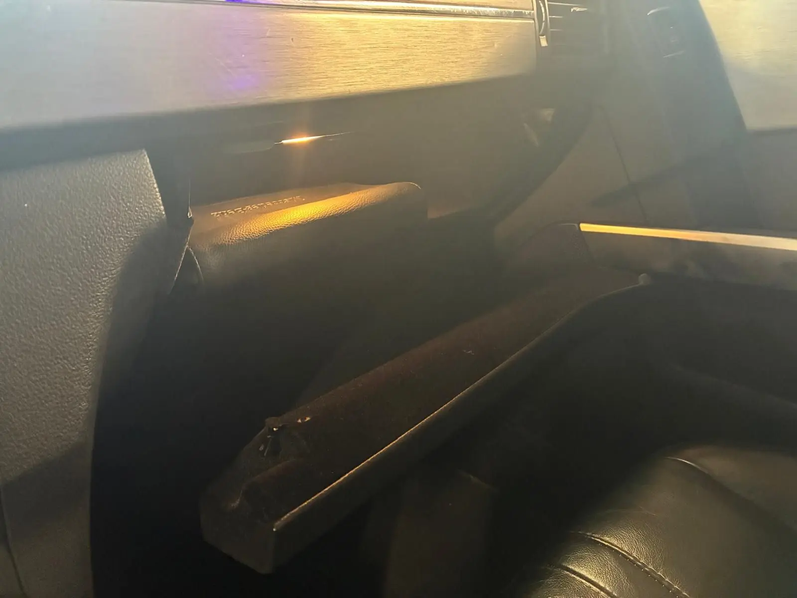 Intérieur noir du Mercedes GLK 220 CDI 2012, vue sur la boîte à gants ouverte côté passager avec éclairage doux.