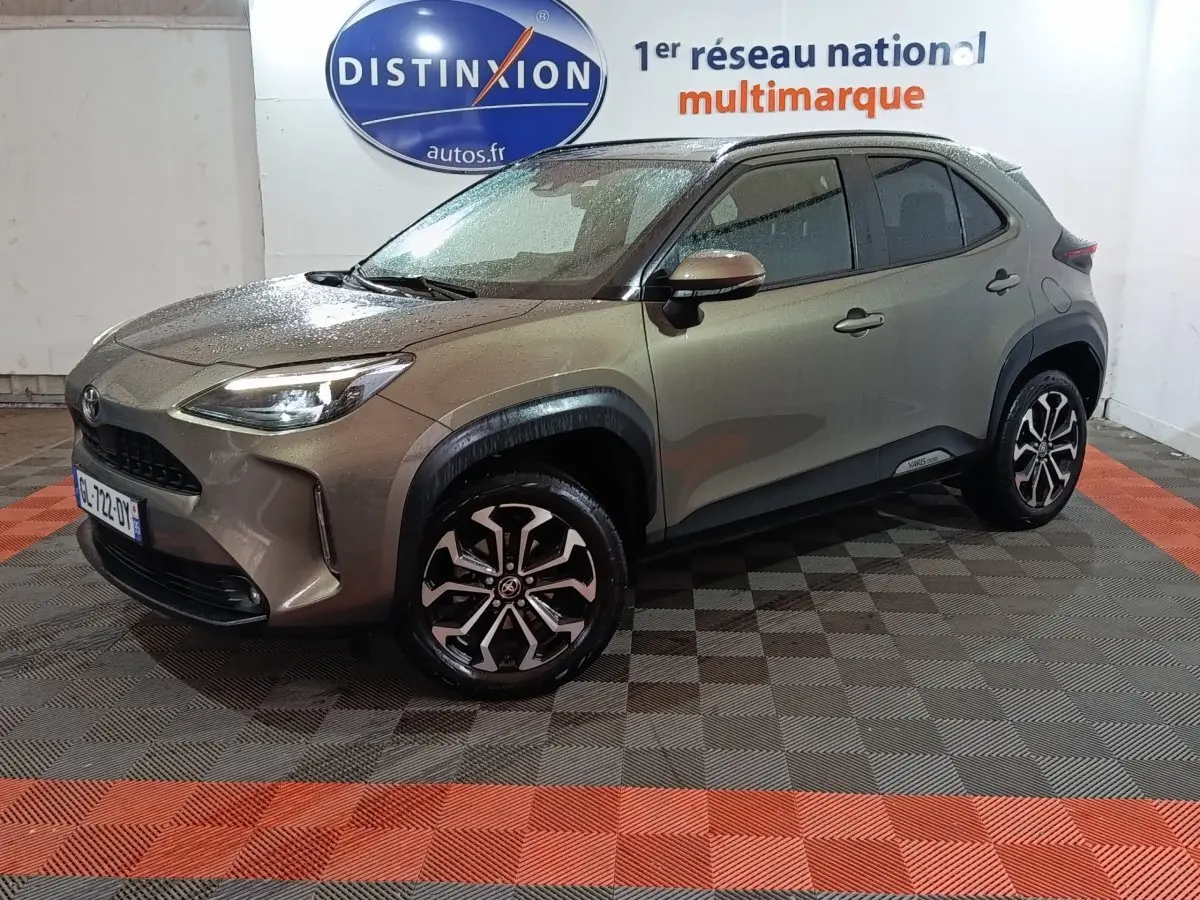 Toyota Yaris Cross gris foncé vue 3/4 avant droit, avec jantes alliage et phares LED allumés.