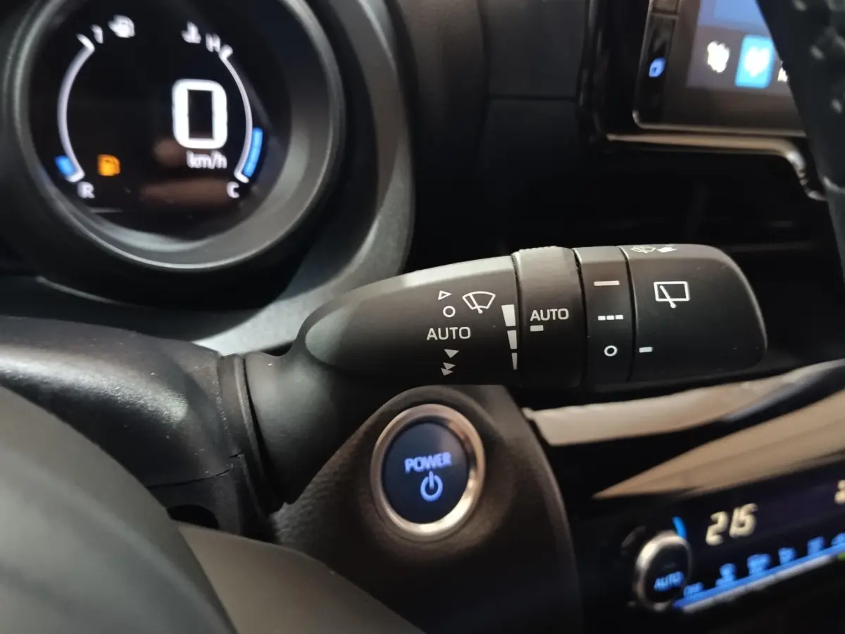Détail intérieur du Toyota Yaris Cross 2022 montrant le bouton Power bleu et la commande d’essuie-glace automatique.