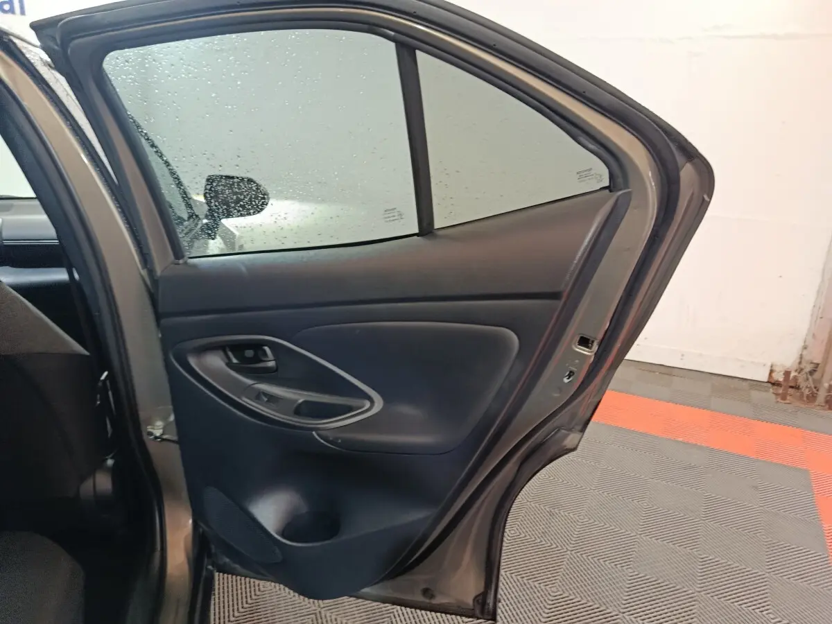 Vue intérieure de la porte arrière droite grise foncée du Toyota Yaris Cross 1.5 Hybrid 2022 avec accoudoir et commandes.