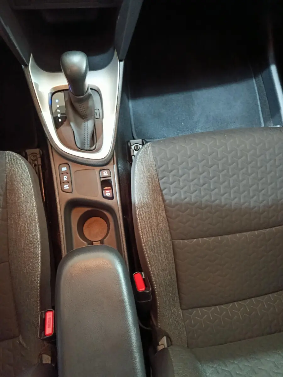 Vue plongeante sur la console centrale et les sièges avant gris du Toyota Yaris Cross 1.5 Hybrid 2022 avec boîte automatique.
