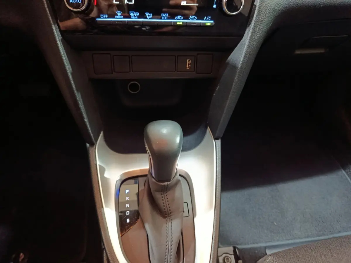 Vue rapprochée du levier de vitesses automatique noir sur console argentée dans l’habitacle du Toyota Yaris Cross gris foncé.
