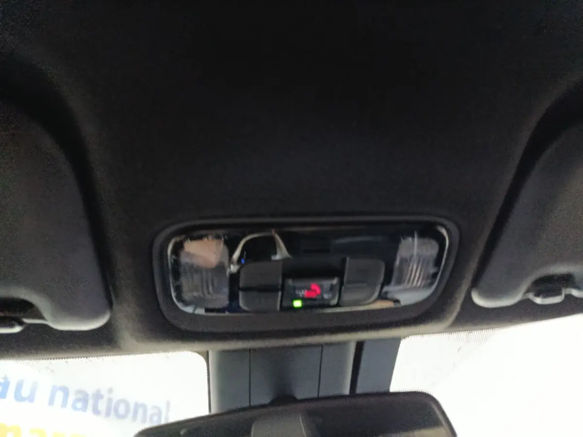 Vue intérieure du plafonnier noir avec commandes d’éclairage et indicateur d’appel d’urgence dans une Toyota Yaris Cross gris foncé.