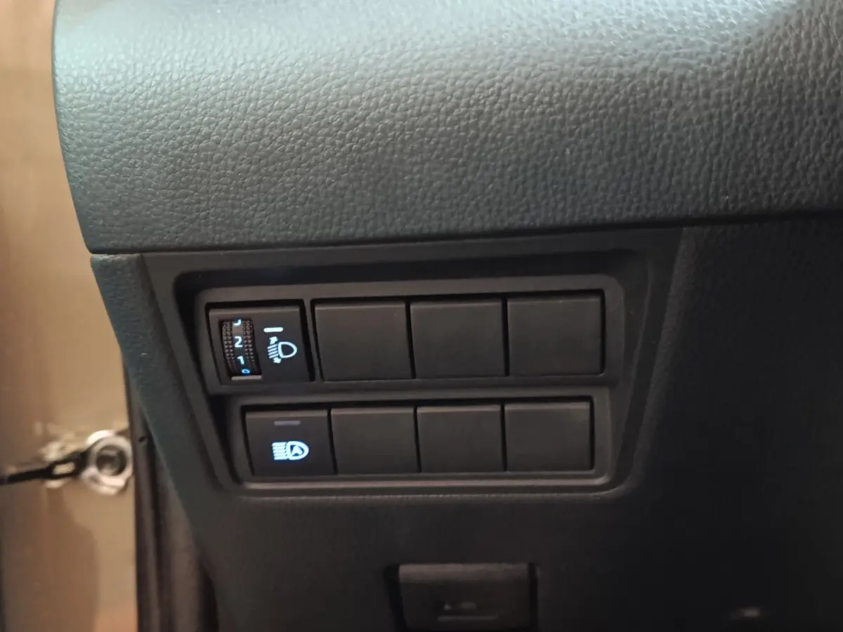 Gros plan sur les commandes d’éclairage à gauche du tableau de bord du Toyota Yaris Cross gris foncé, version hybride 2022.