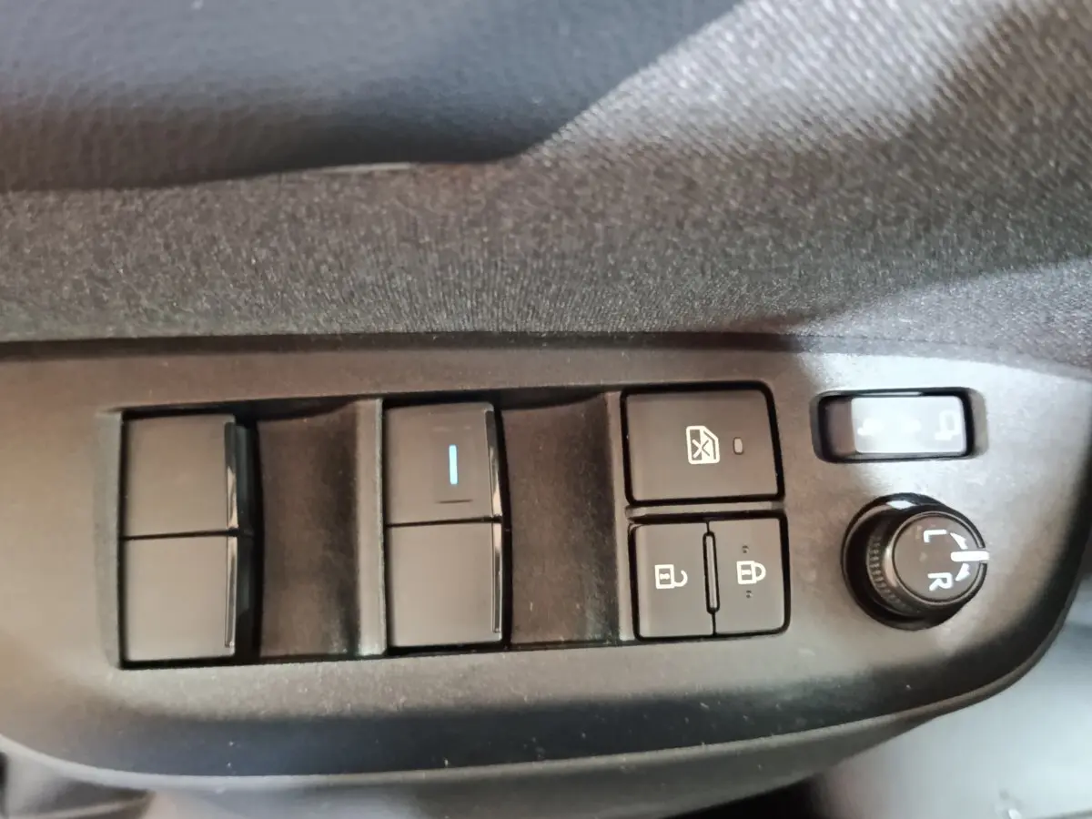 Gros plan sur les commandes de réglage des vitres et des rétroviseurs côté conducteur du Toyota Yaris Cross gris foncé 2022.