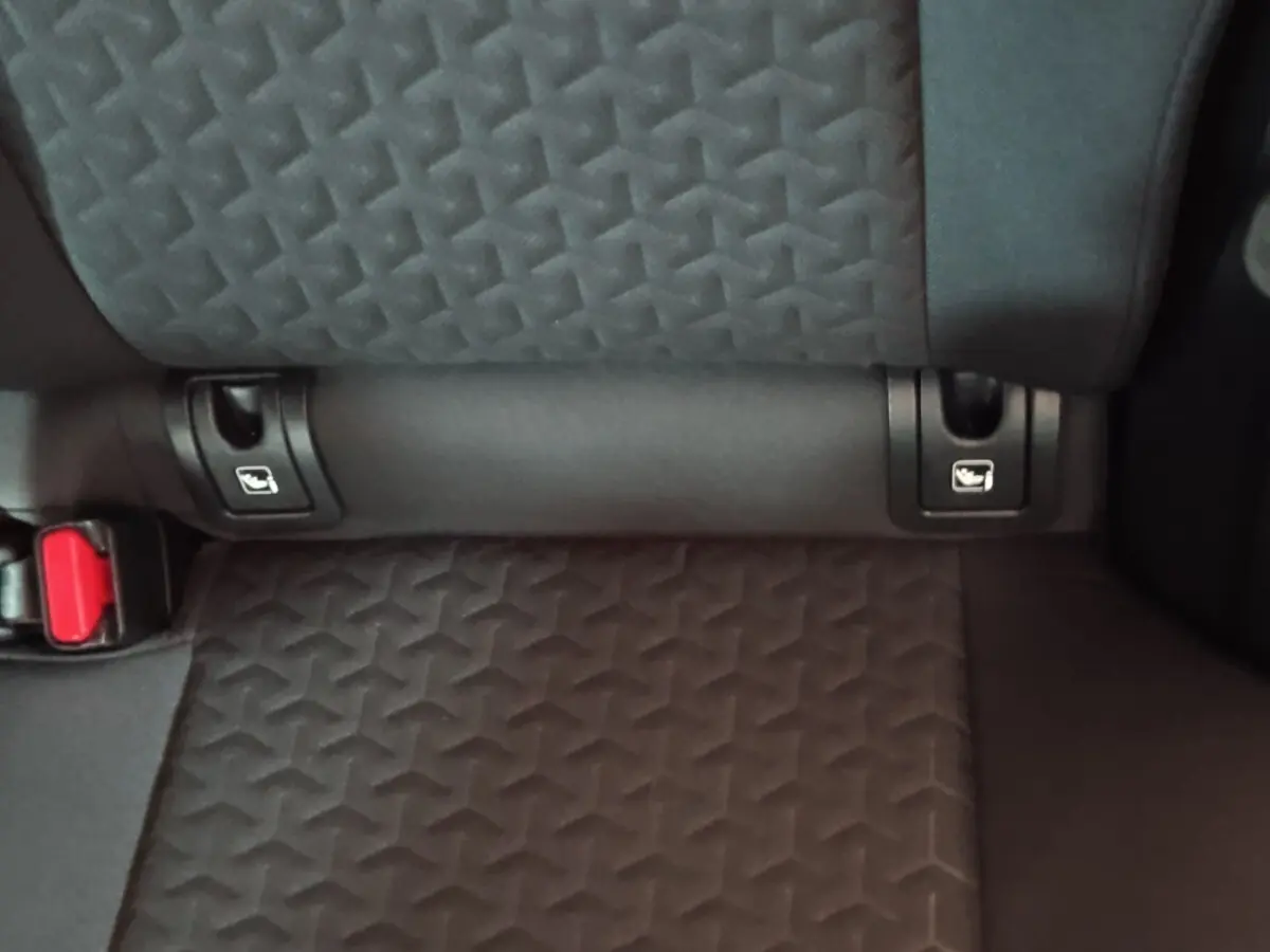 Gros plan sur la banquette arrière grise foncée de la Toyota Yaris Cross 2022, montrant les fixations Isofix et la boucle de ceinture rouge.