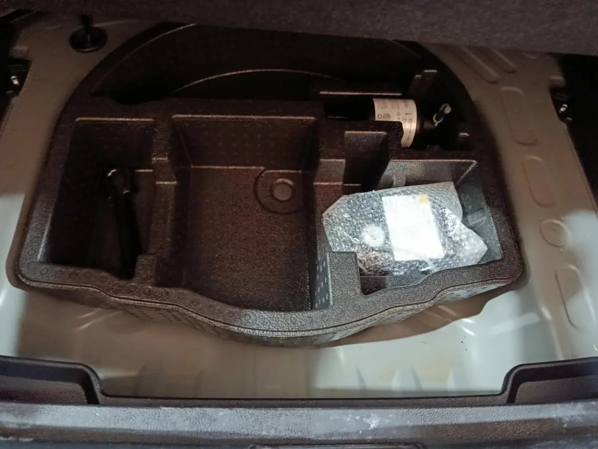 Compartiment de rangement sous le plancher du coffre de la Toyota Yaris Cross 1.5 Hybrid gris foncé, vue plongeante.