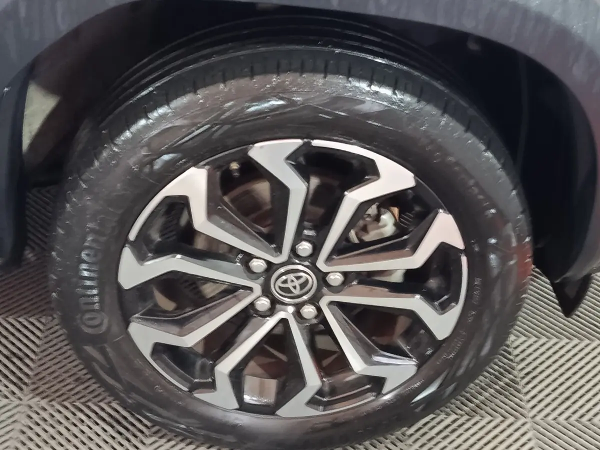 Gros plan sur la roue avant droite du Toyota Yaris Cross gris foncé, avec jante alliage au design géométrique noir et argent.