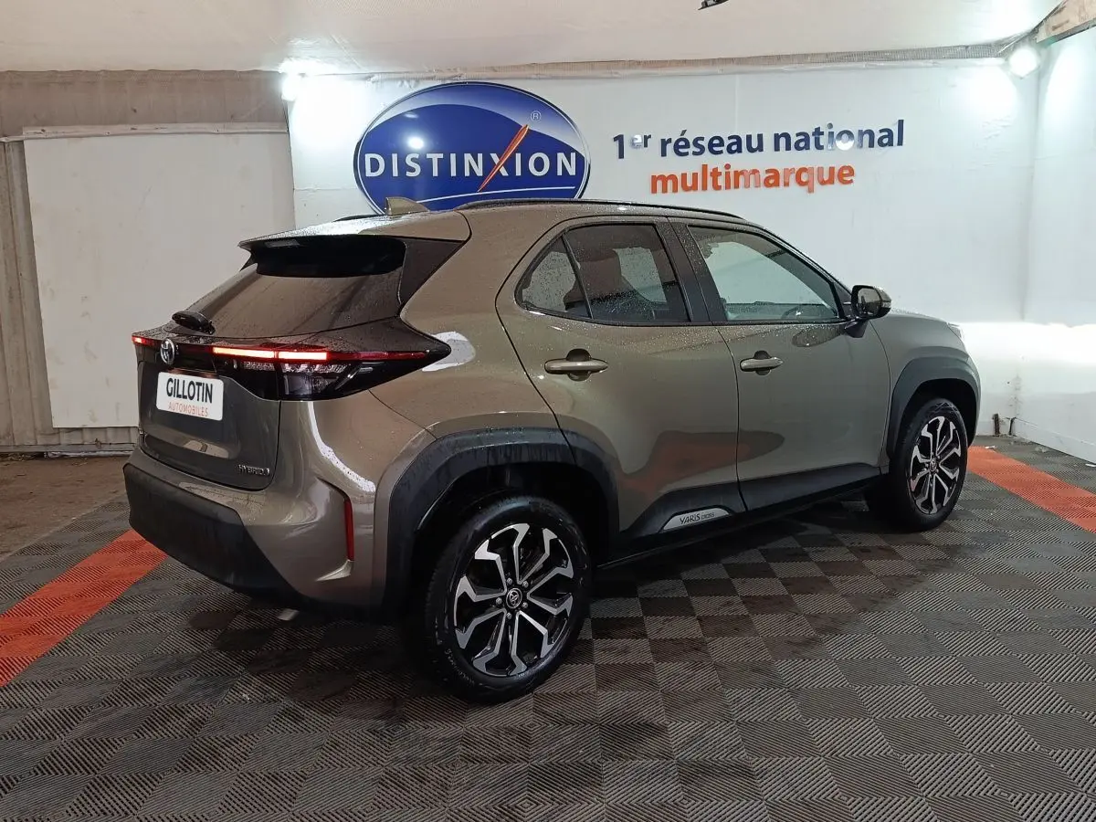 Vue 3/4 arrière droite d'une Toyota Yaris Cross gris foncé avec feux arrière LED et jantes alliage distinctives.