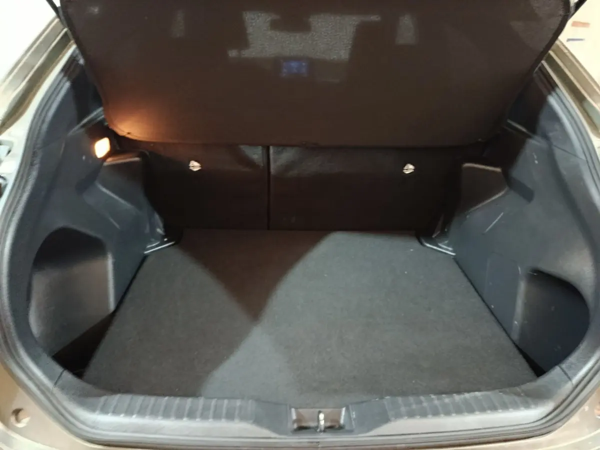 Coffre ouvert de la Toyota Yaris Cross gris foncé, montrant un espace de chargement propre et bien éclairé.