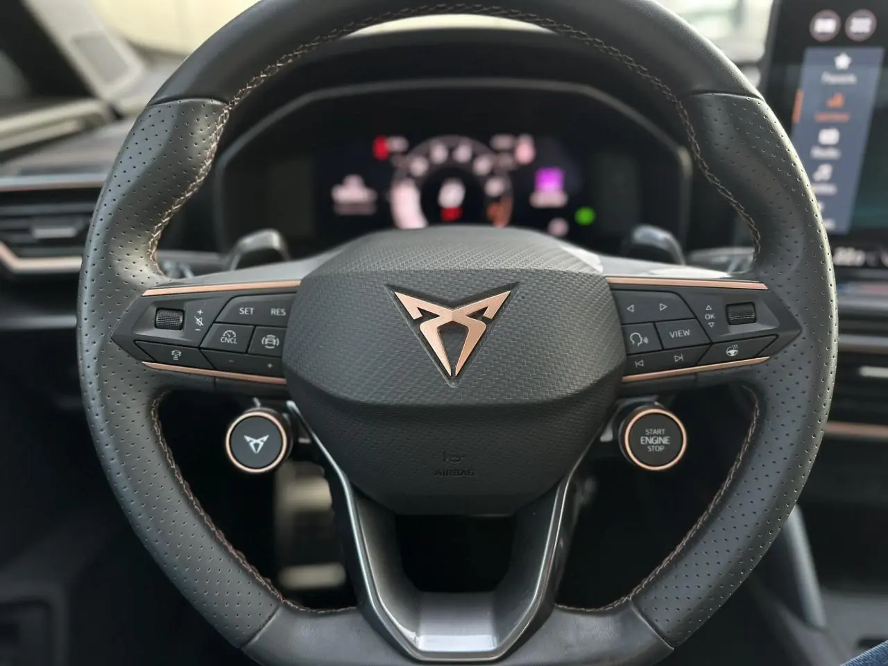 Volant cuir perforé avec logo CUPRA cuivré et commandes intégrées, intérieur moderne du Formentor 2025.