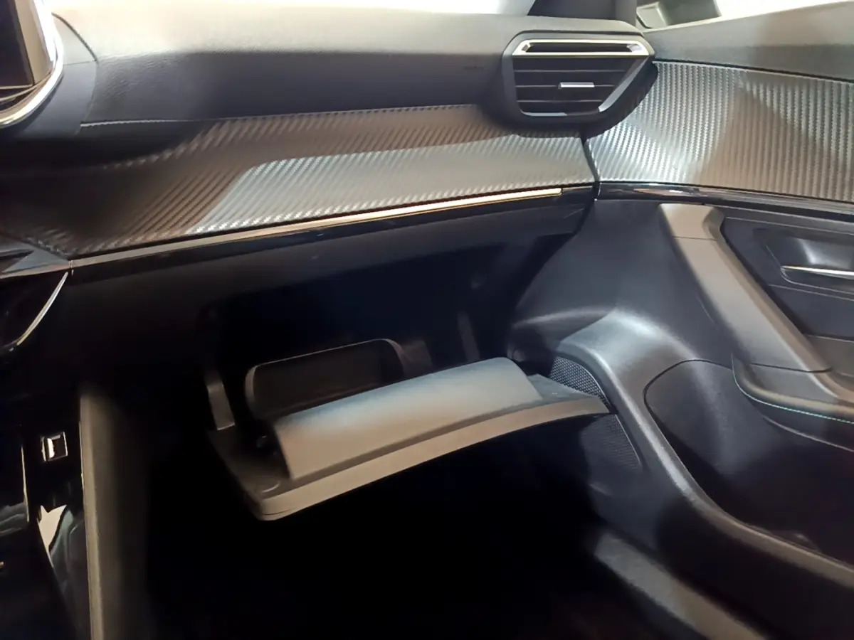 Vue intérieure côté passager du Peugeot 2008 blanc 2021, avec boîte à gants ouverte et tableau de bord noir texturé.